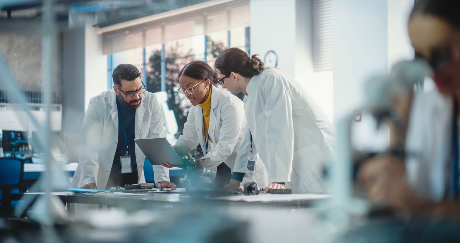 Researchers collaborating over a laptop in a lab